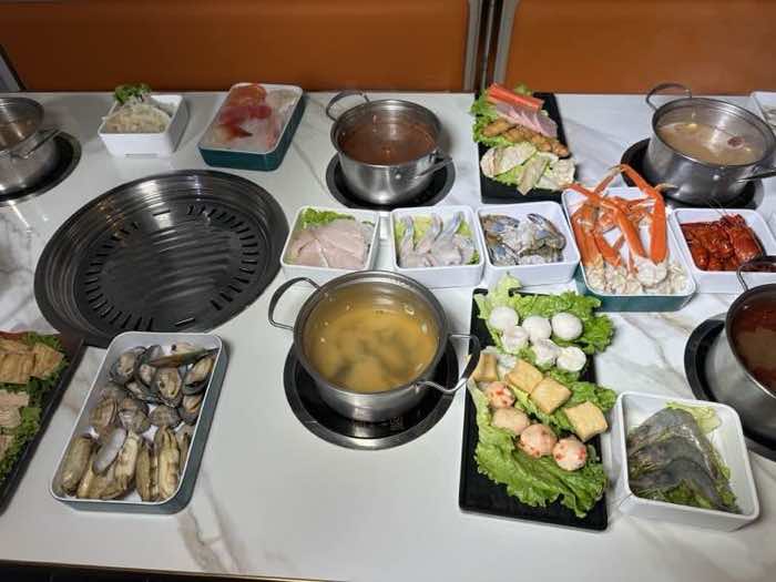 Clams, crab and the full table spread Clams, crab legs, prawns and fish balls laid out around a built-in grill and broth pots