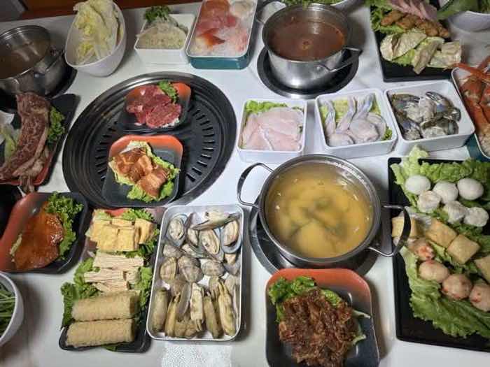 Clams, fish cake, sliced fish and marinated meats set around a built-in grill and a broth pot