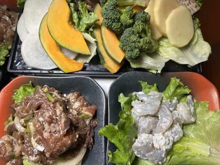 Sliced pumpkin, broccoli and radish on one tray with marinated beef and marinated chicken on another